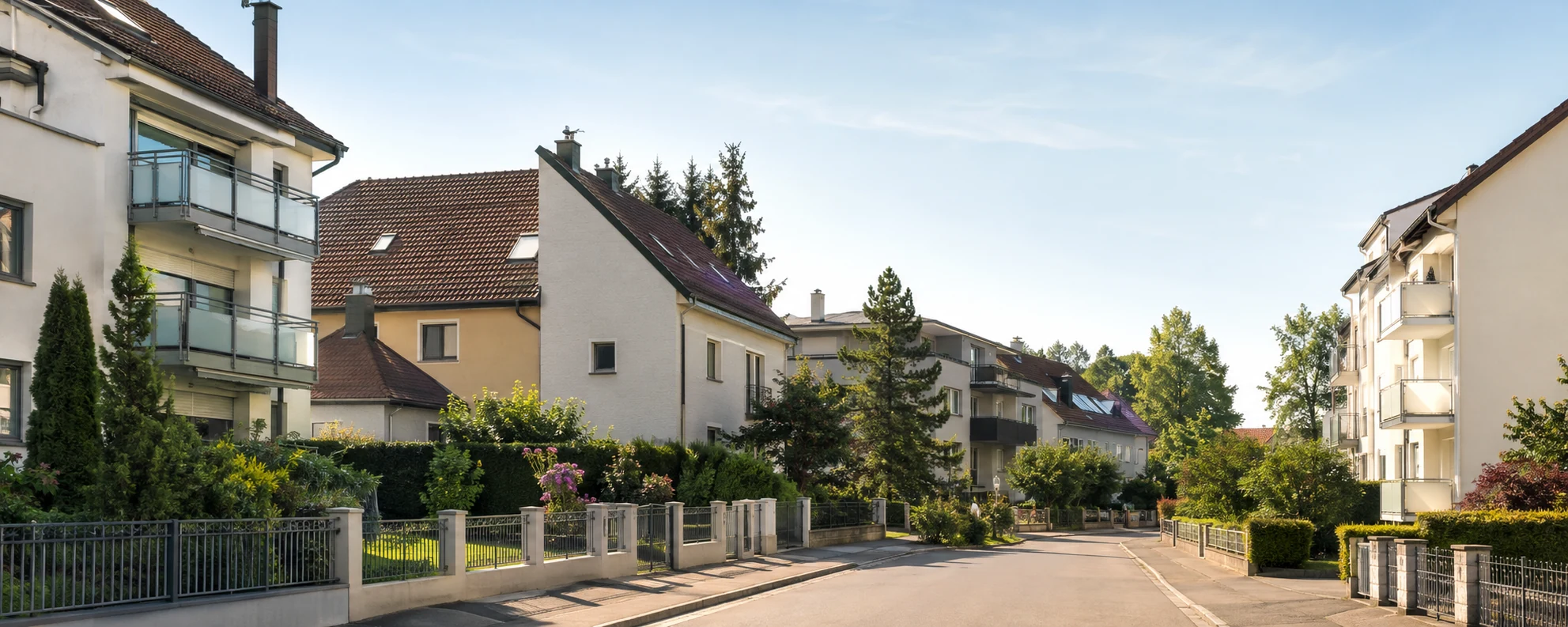 Österreichische Wohnstraße mit Häusern, Balkonen und begrünten Außenflächen